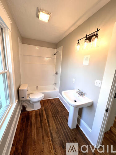 A bathroom with wooden floors and white fixtures.