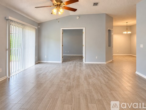 A spacious room with a ceiling fan and lighting fixture.