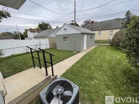 A backyard with a fan and a concrete walkway.
