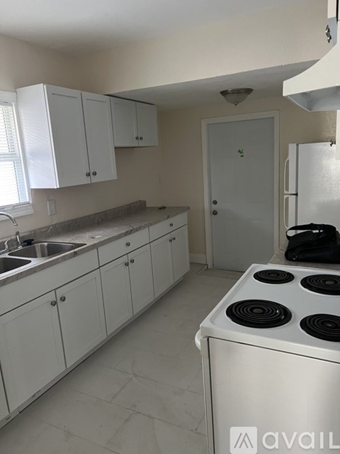 A kitchen with white cabinets and a white stove top oven.