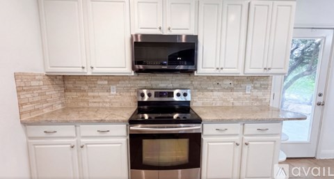 A kitchen with white cabinets and a black stove top oven.