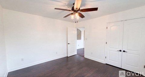 A room with a ceiling fan and wooden floors.