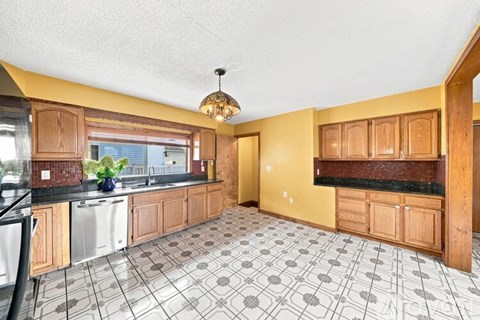 A kitchen with wooden cabinets and a tiled floor.