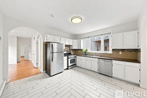 A kitchen with white cabinets and a tile floor.