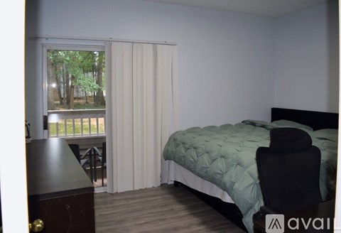 A bedroom with a bed, chair, and window with blinds.