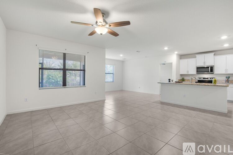A spacious living room with a ceiling fan and tiled flooring.