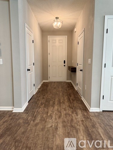 A hallway with wood flooring and white walls.
