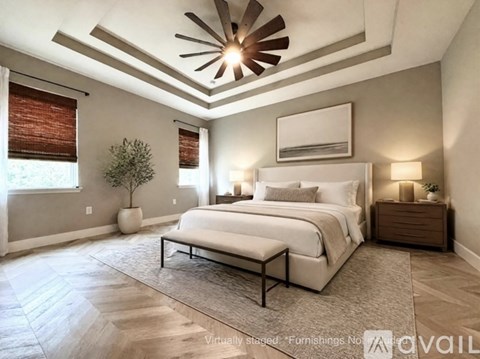 A bedroom with a large bed, a ceiling fan, and a rug on the floor.