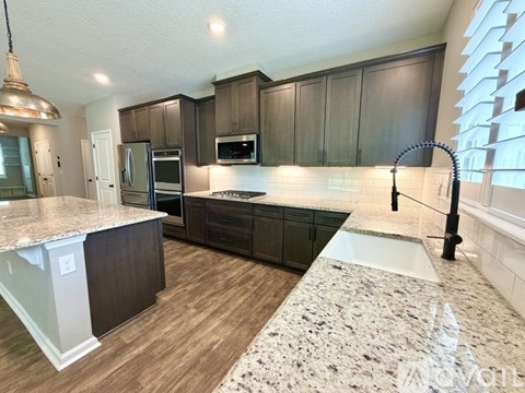 A kitchen with dark wood cabinets and a marble countertop.