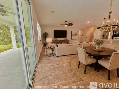 A living room with a dining table and chairs, a television, and a chandelier.