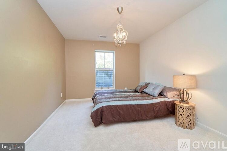 A bedroom with a bed, pillows, a lamp, and a chandelier.