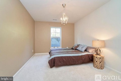 A bedroom with a bed, pillows, a lamp, and a chandelier.