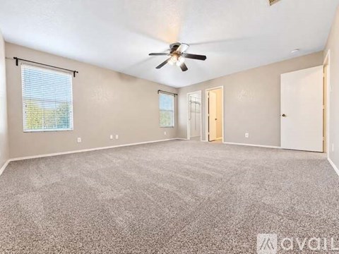 A spacious room with a ceiling fan and carpeted floor.