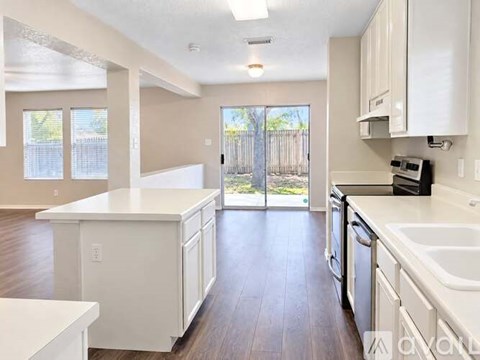 A kitchen with white cabinets and a wooden floor.