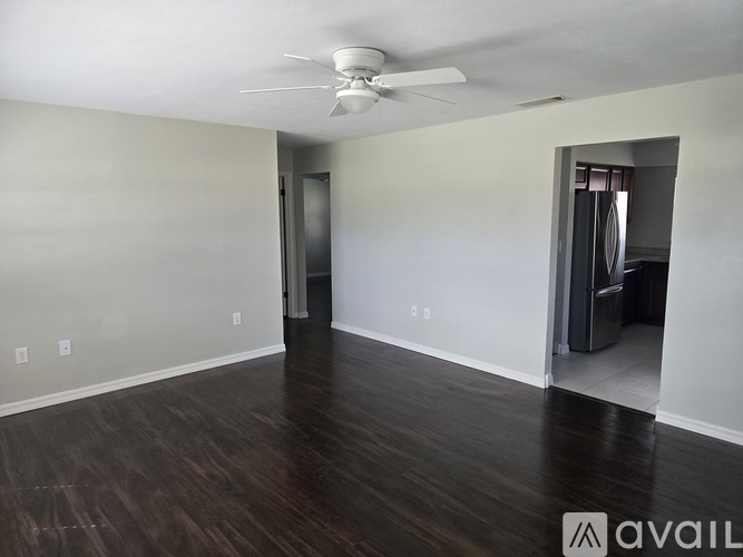 A room with a ceiling fan and wooden flooring.