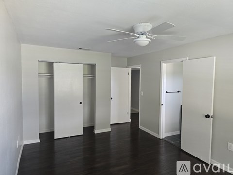 A spacious room with a ceiling fan and multiple doors.