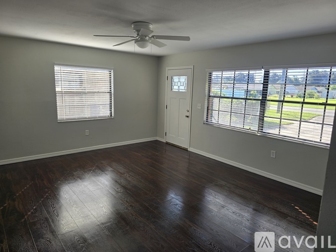 A room with a ceiling fan and wooden flooring.