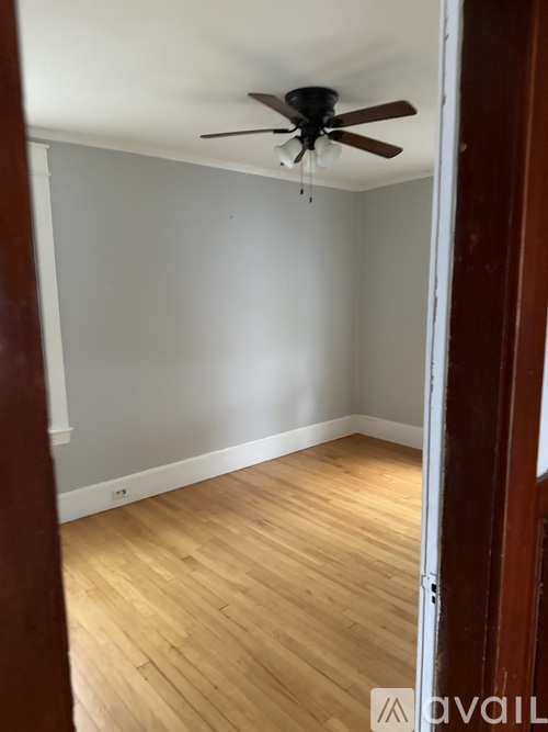 A room with a ceiling fan and wooden flooring.