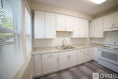 A kitchen with white cabinets and a marble countertop.