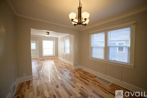 A room with wooden floors and a chandelier hanging from the ceiling.