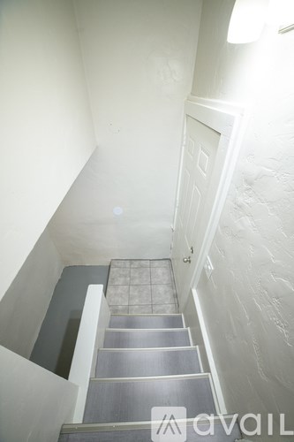 A staircase with a metal railing and steps leading up to a door.