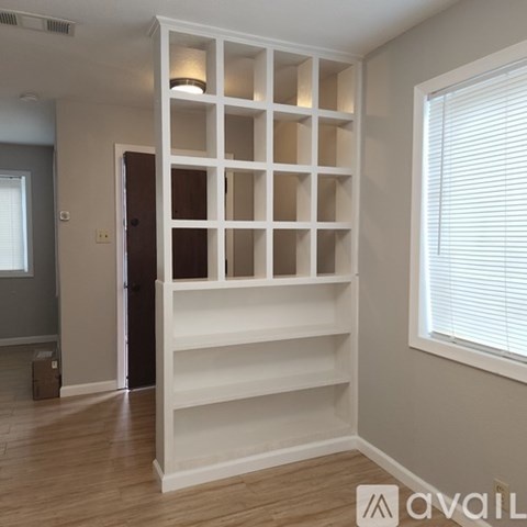 A room with a white shelving unit and a window with blinds.