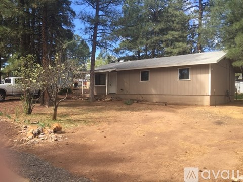 A house with a brown roof and a brown fence is surrounded by trees.