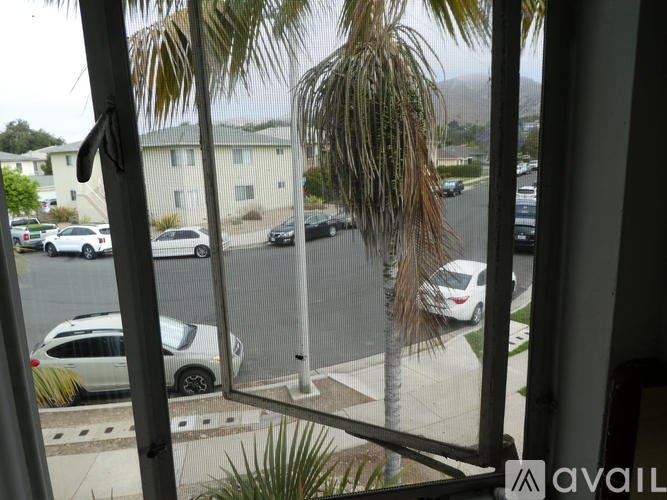 A view from a window looking out at a street with cars and houses.