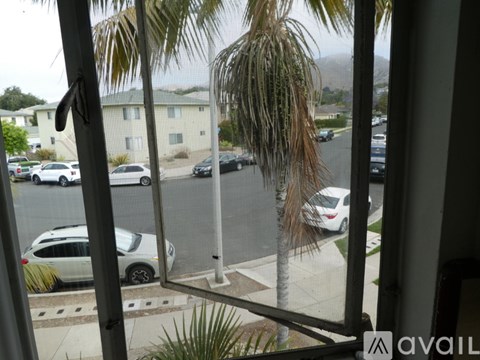 A view from a window looking out at a street with cars and houses.