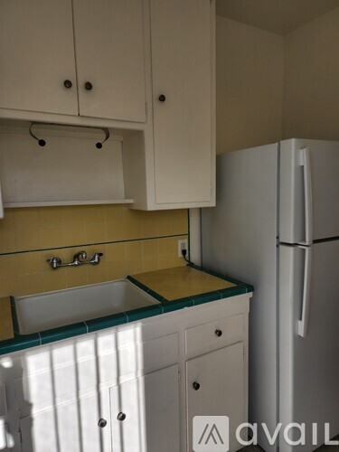 A kitchen with white cabinets and a white refrigerator.