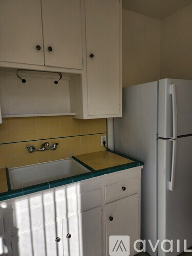 A kitchen with white cabinets and a white refrigerator.