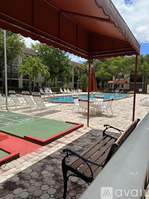 A pool area with a red and green pool and a bench under a canopy.