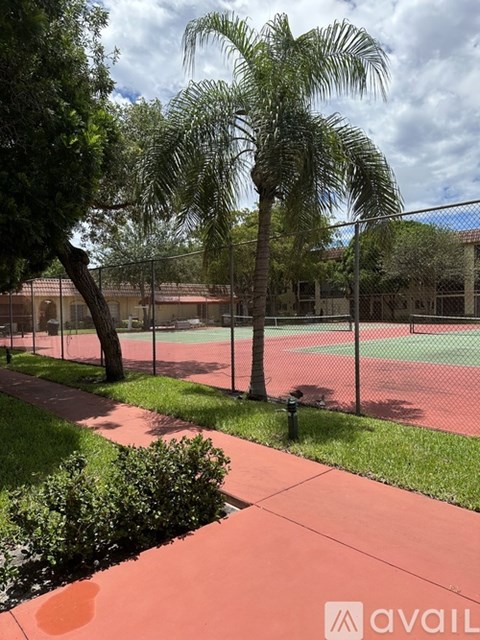 A tennis court is surrounded by a fence and trees.