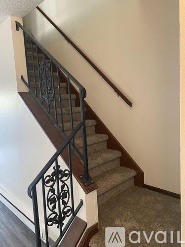 A staircase with a metal railing and a carpeted runner.