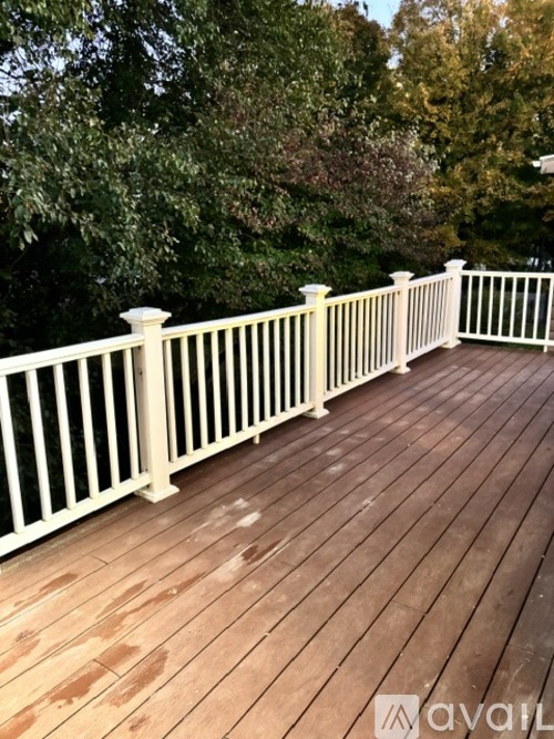 A wooden deck with white railings and trees in the background.