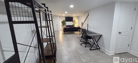 A staircase with a metal railing leads to a bedroom with a bed and a desk.