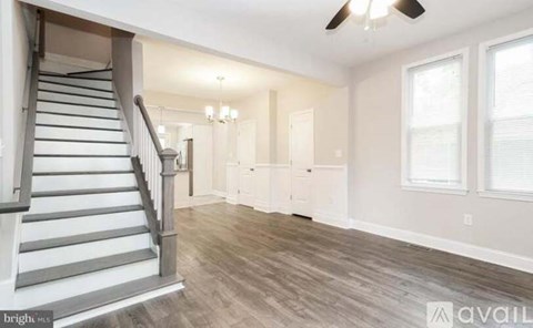 A spacious room with a staircase and a ceiling fan.
