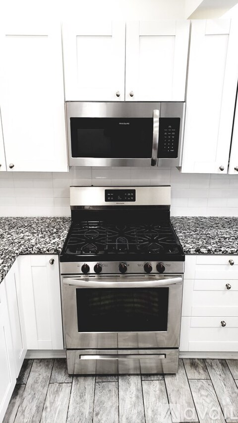 A modern kitchen with a stove top oven and microwave above it.