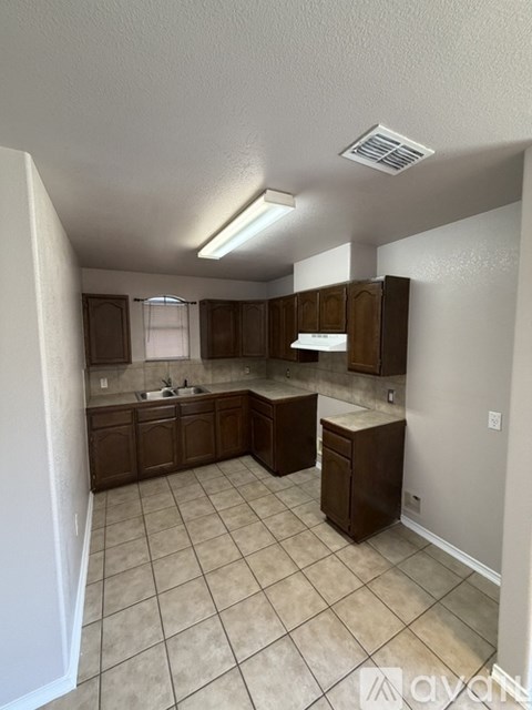 A kitchen with brown cabinets and a tiled floor.