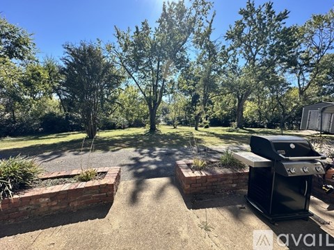 A backyard with a BBQ grill and a brick wall.