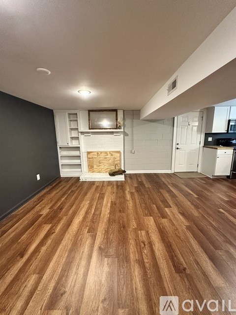 A room with wooden flooring and a fireplace in the middle.