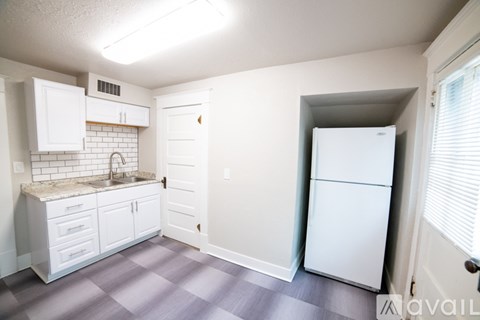 A kitchen with white cabinets and a white refrigerator.