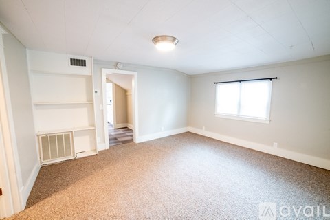 A spacious room with a window and carpeted floor.