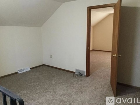 A room with a carpeted floor and a door leading to another room.