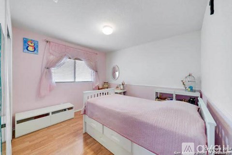 A pink bedroom with a white bed and a window with white curtains.