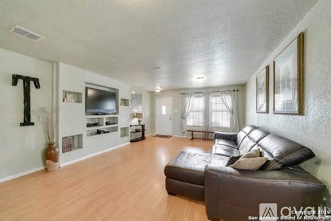 A living room with a brown leather couch and a wooden floor.