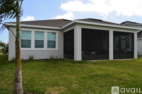 A house with a white exterior and a brown roof is surrounded by a grassy lawn.