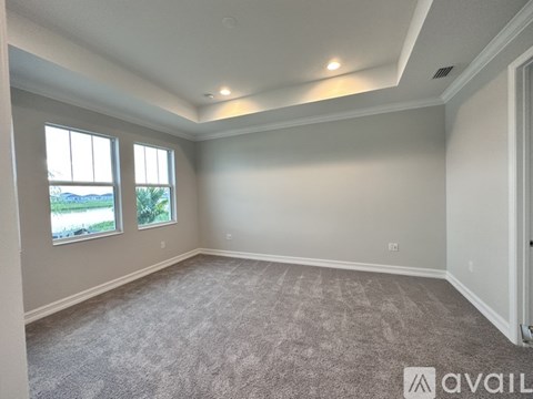 A spacious room with carpeted floor and two windows.