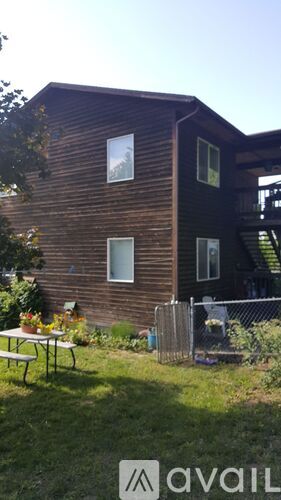 A wooden house with a patio table and chairs in front.