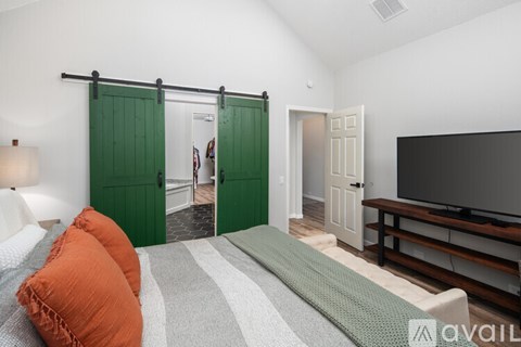A bedroom with a bed, pillows, and a television.